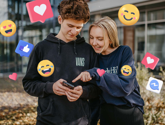 Ein Junge und ein Mädchen schauen gemeinsam auf ein Smartphone. Um sie herum viele Emojis.